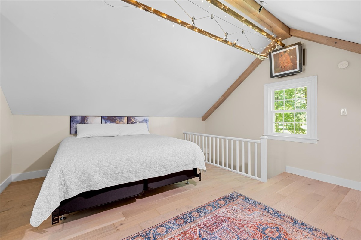 Upper level bedroom with exposed beams and string lights